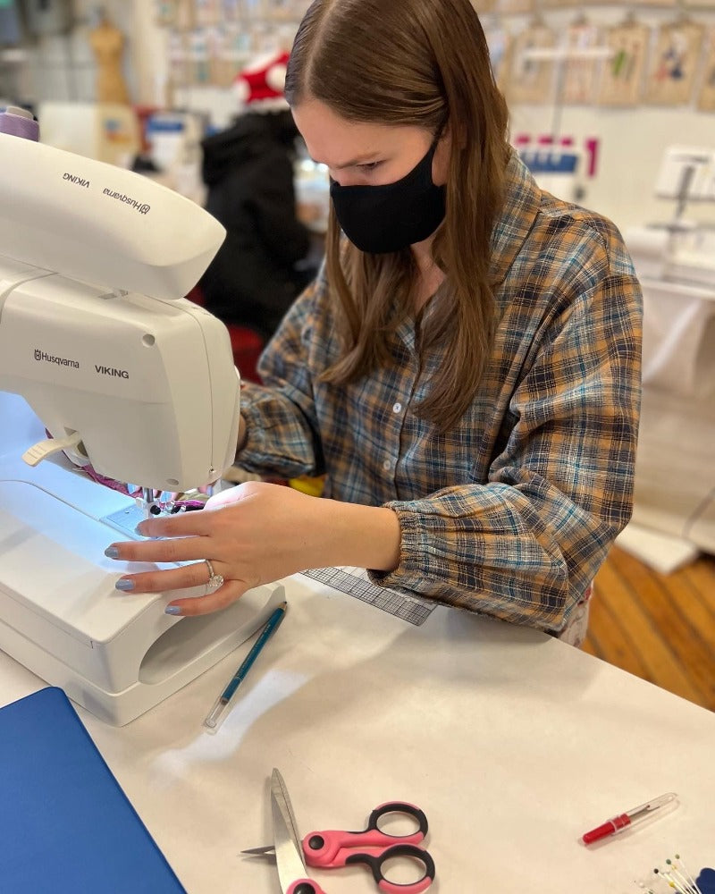 girl with plaid shirt sewing on a machine in Chicago