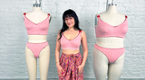 Woman standing between two mannequins wearing a pink bikini set against a white brick wall.
