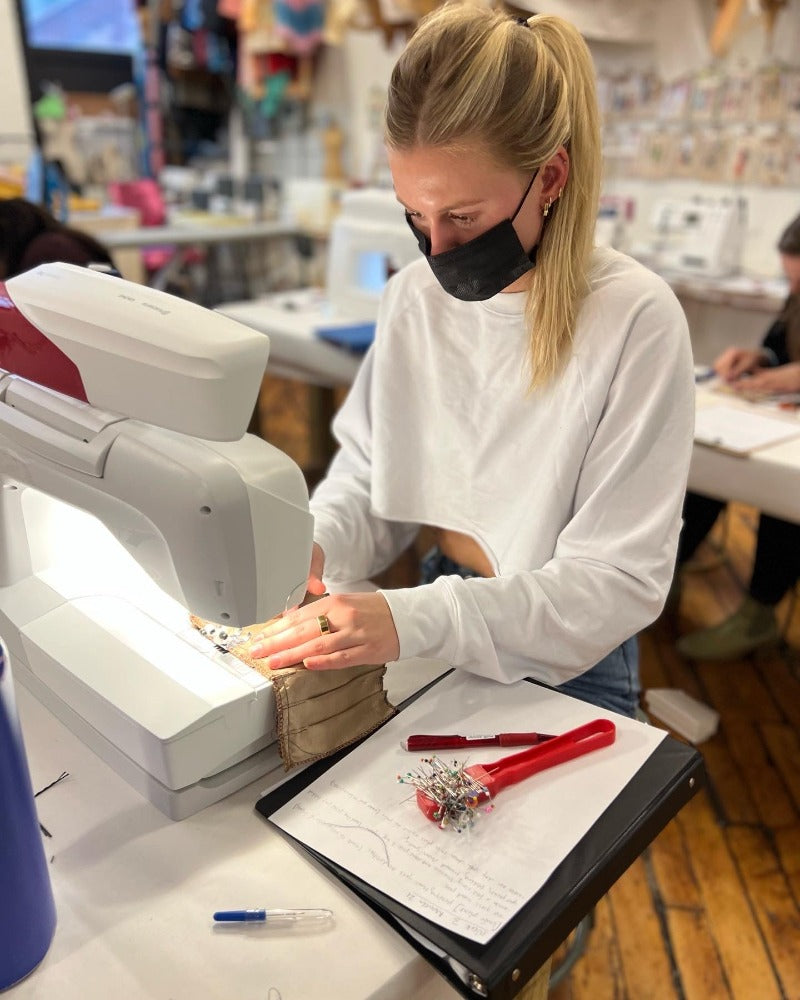 girl in crop top sewing at a machine
